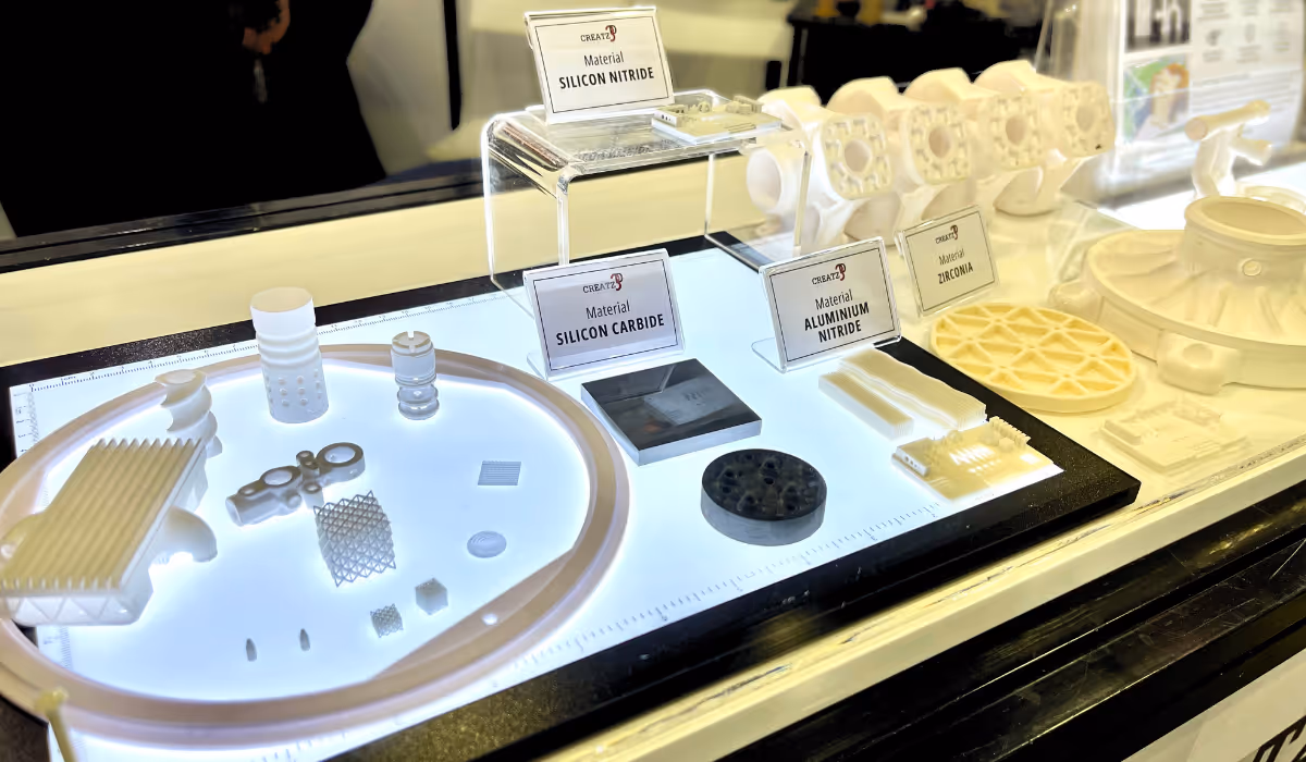 Display of various ceramic materials and components labeled as Silicon Nitride, Silicon Carbide, Aluminum Nitride, and Zirconia on a lighted table.