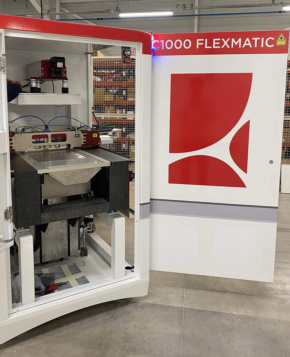 Open white and red industrial ceramic printer labeled C1000 FLEXMATIC inside a manufacturing facility.