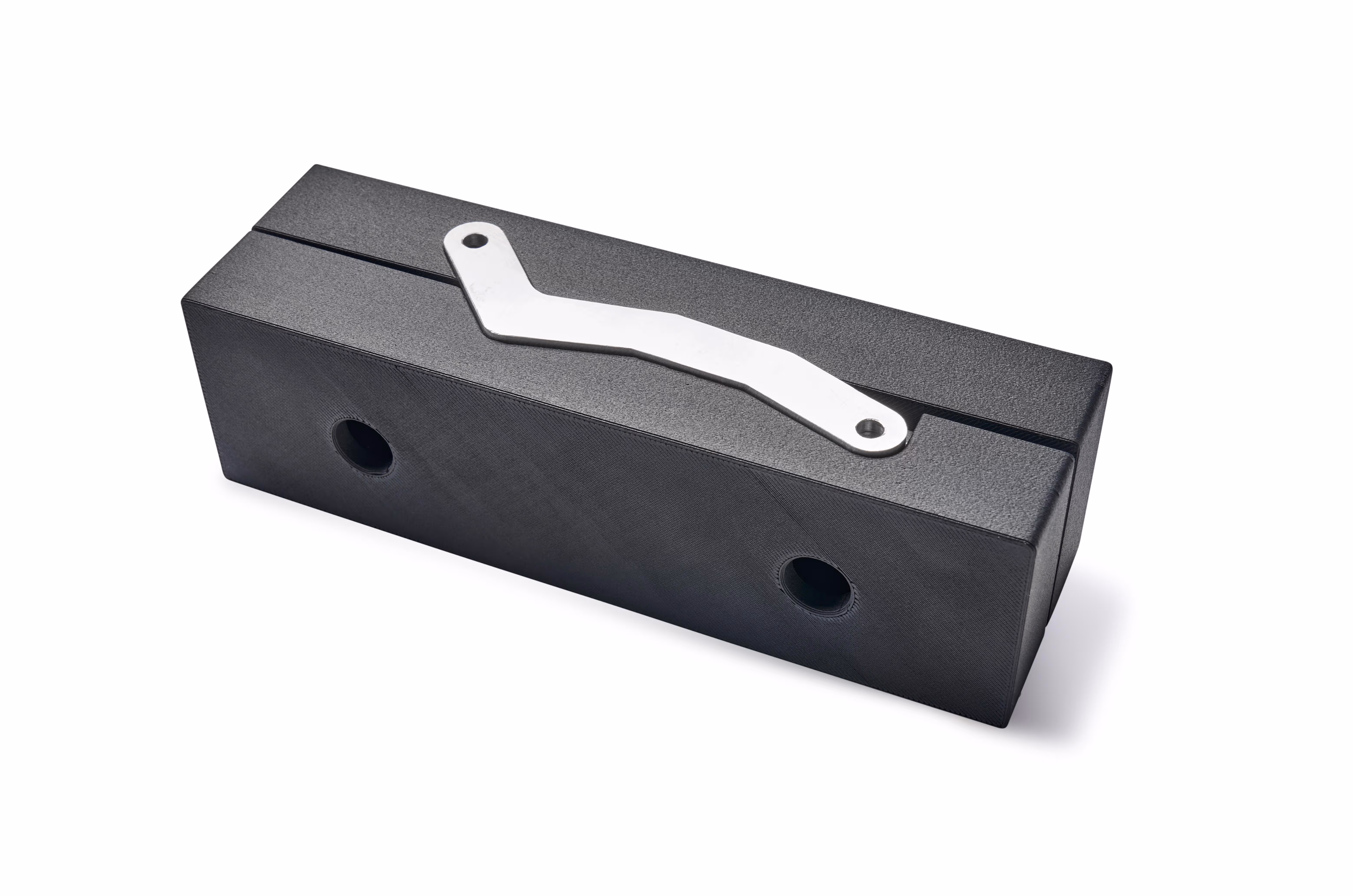 Black rectangular soft jaw tool with two circular holes and a metal bracket on top.