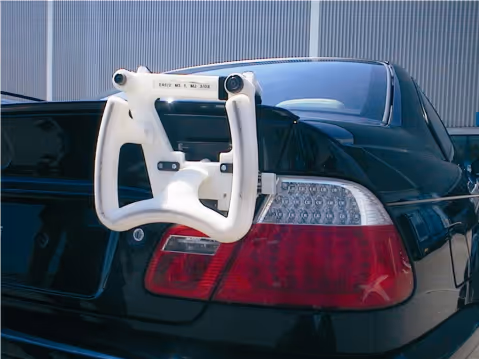White rear wheel alignment jig attached to the back of a black car with visible taillights.