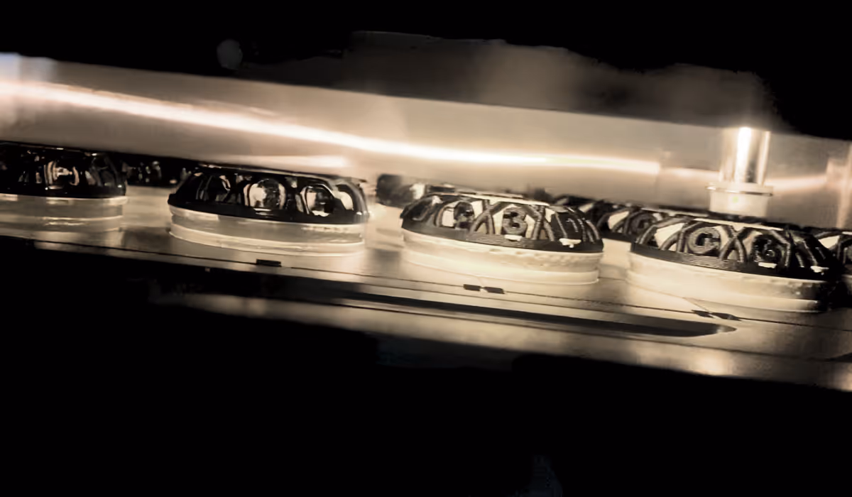 Close-up view of circular mechanical parts with gears and intricate patterns arranged in a row on a metallic surface under dim lighting.