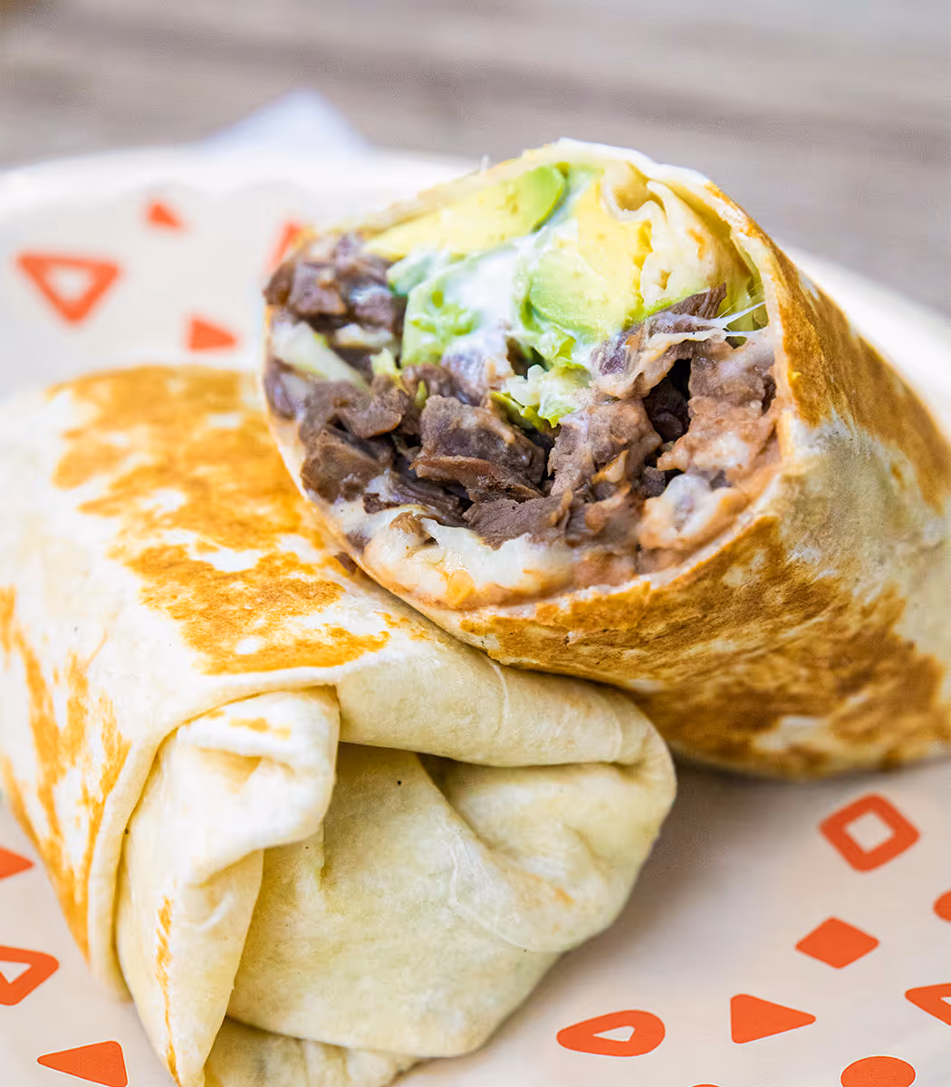 Grilled beef burrito with avocado, beans, and cheese, cut in half and served at Tacos Yoyo, a Mexican taquería in Miami.