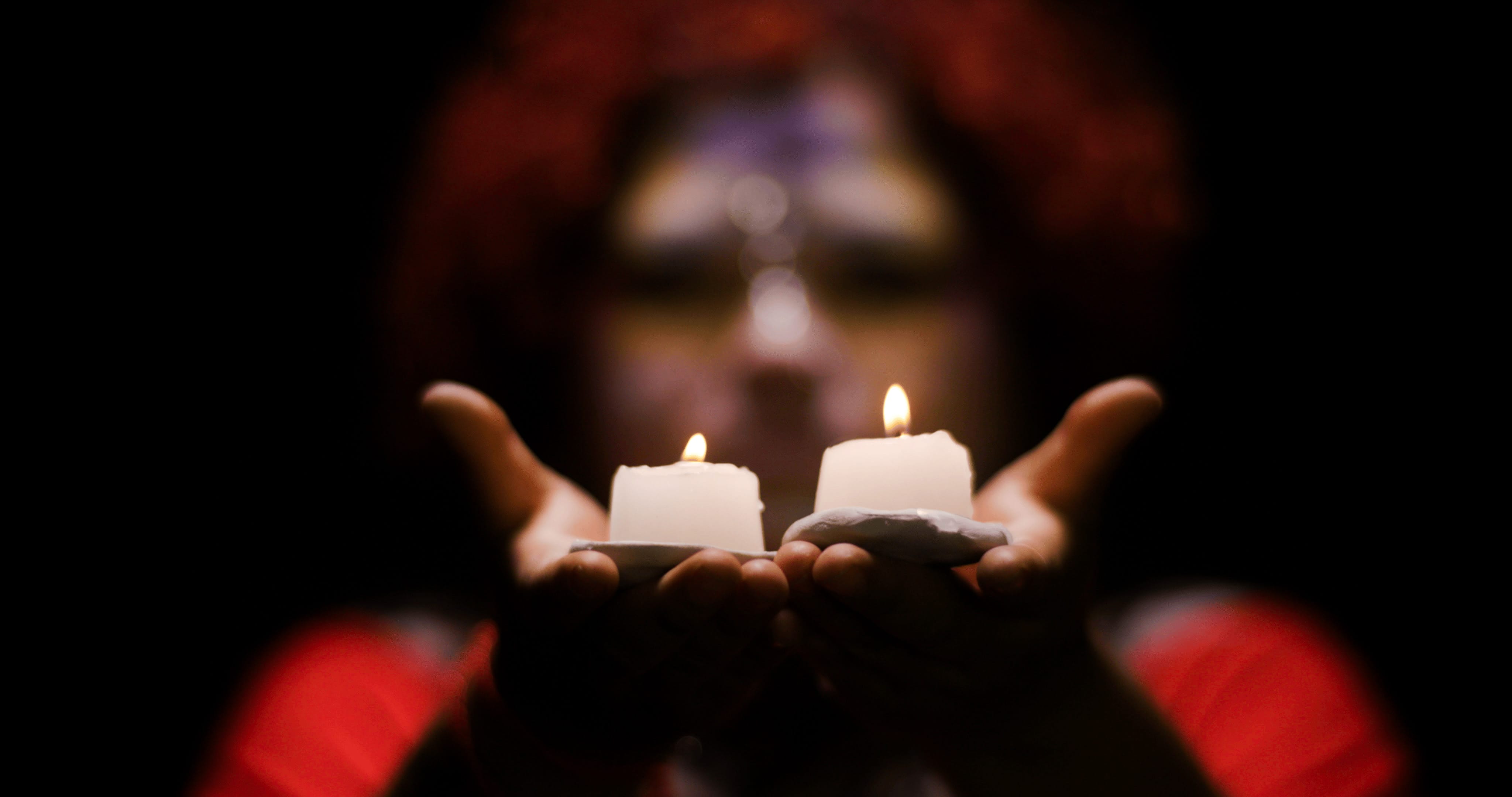 Young woman in costume holding two lit candles
