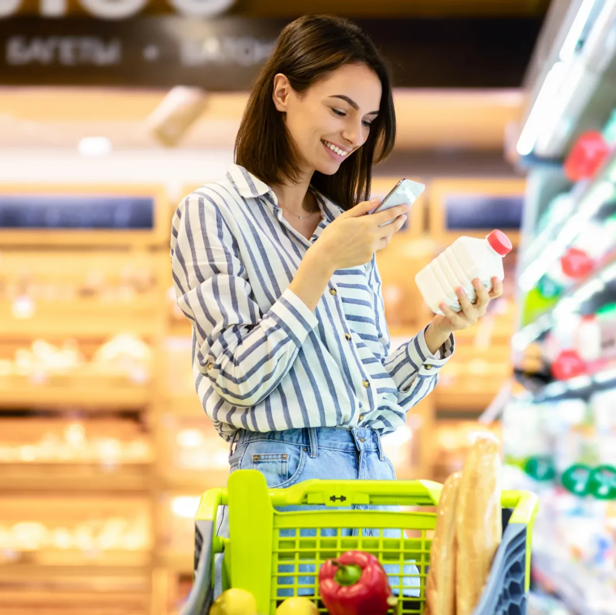 Shopper in a supermarket scanning a milk bottle with her phone