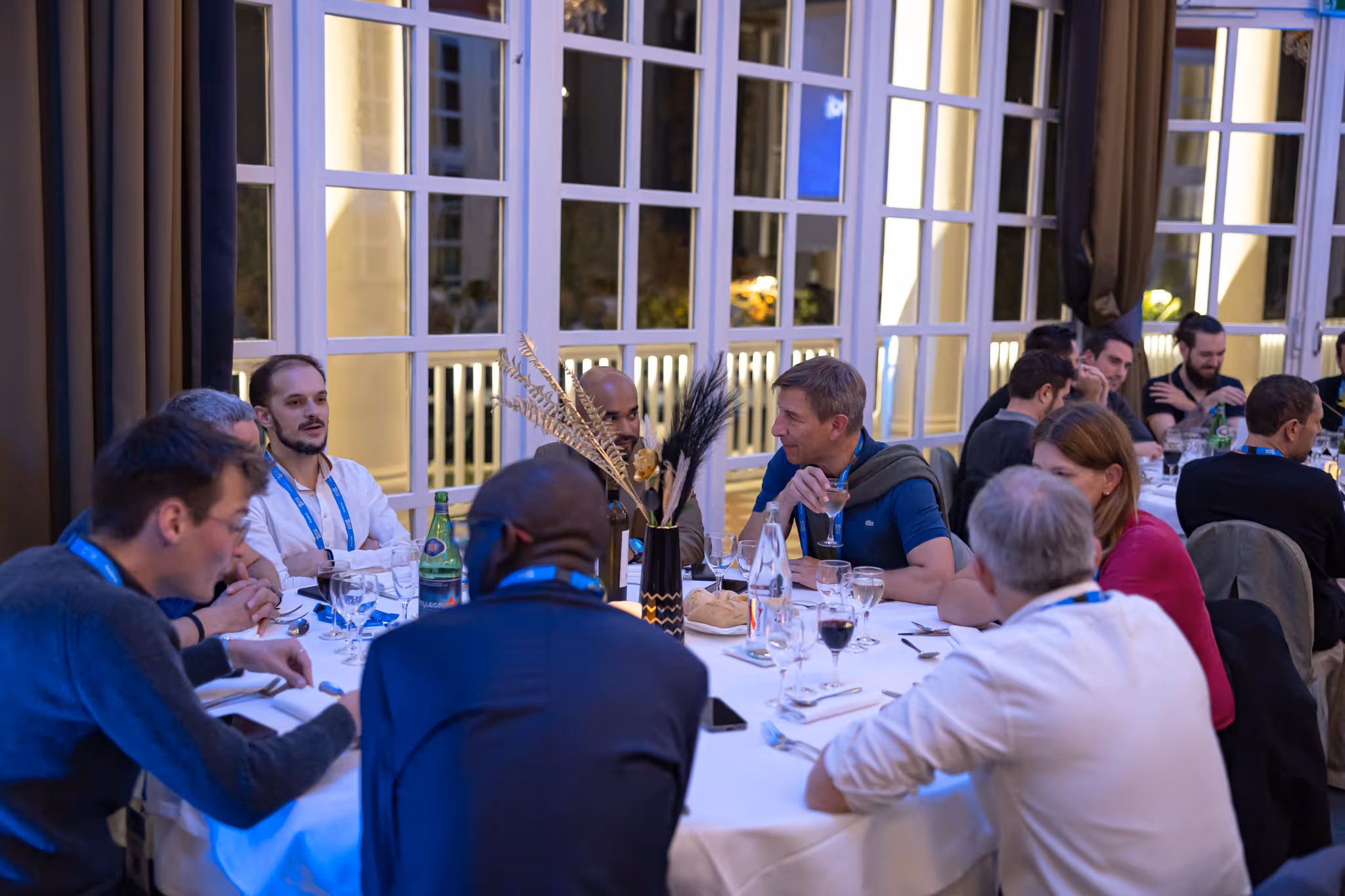 People seated around a restaurant table, engaging in a group discussion during a meal.