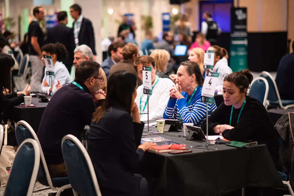 People sitting at tables discuss in groups at a conference or meeting.