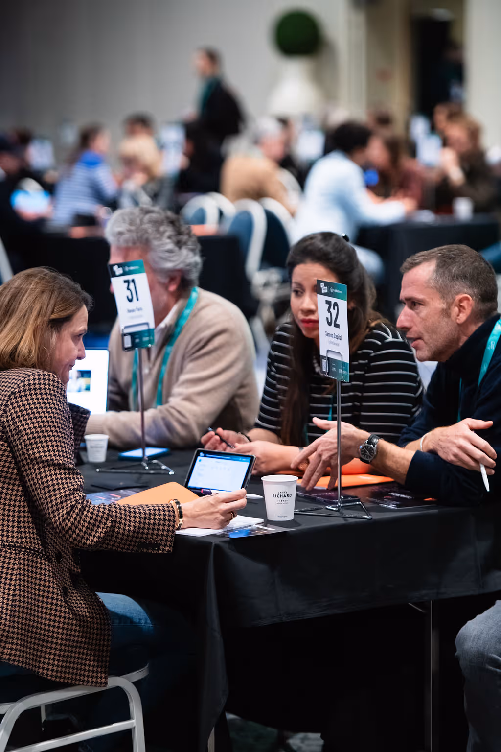 People sitting at tables having discussions during a conference or meeting event.