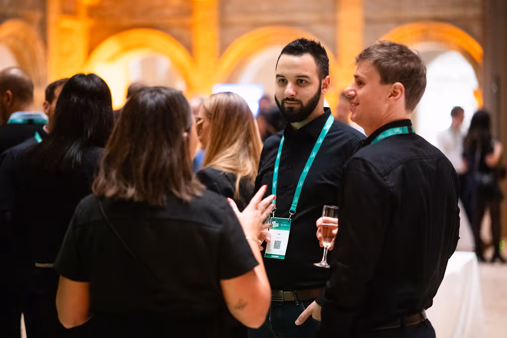 A group of people in conversation at a social event, wearing name tags.
