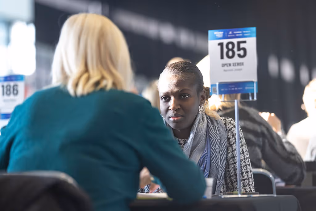 Two people are talking across a table at a business networking event.