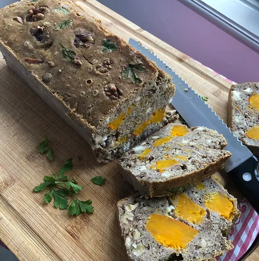 Cake salé au potimarron, feta, noix et farine sans gluten, tranché sur une planche en bois avec persil frais