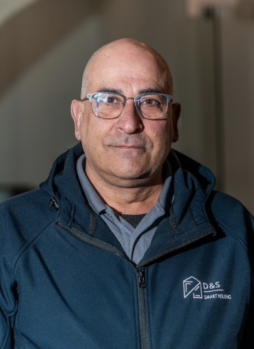 Portrait of a middle-aged man with glasses wearing a dark blue D&S Smart Housing jacket.