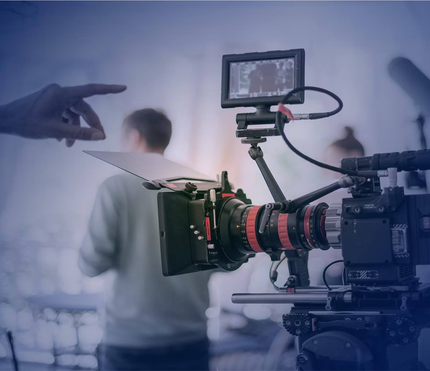 Professional video camera on a film set recording while a director points in the background