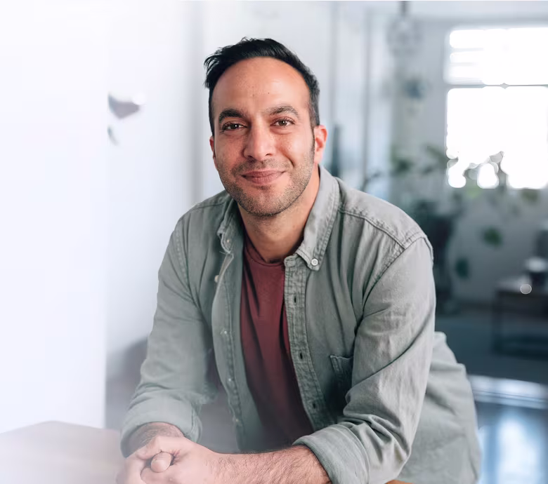 Ido Assaf smiling, leaning on a table in a bright room