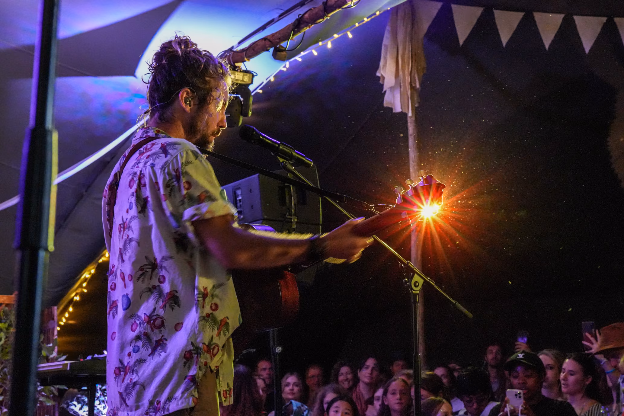 Jeremy Loops playing guitar on stage under warm spot lighting at a Greenpop outdoor music and festival event