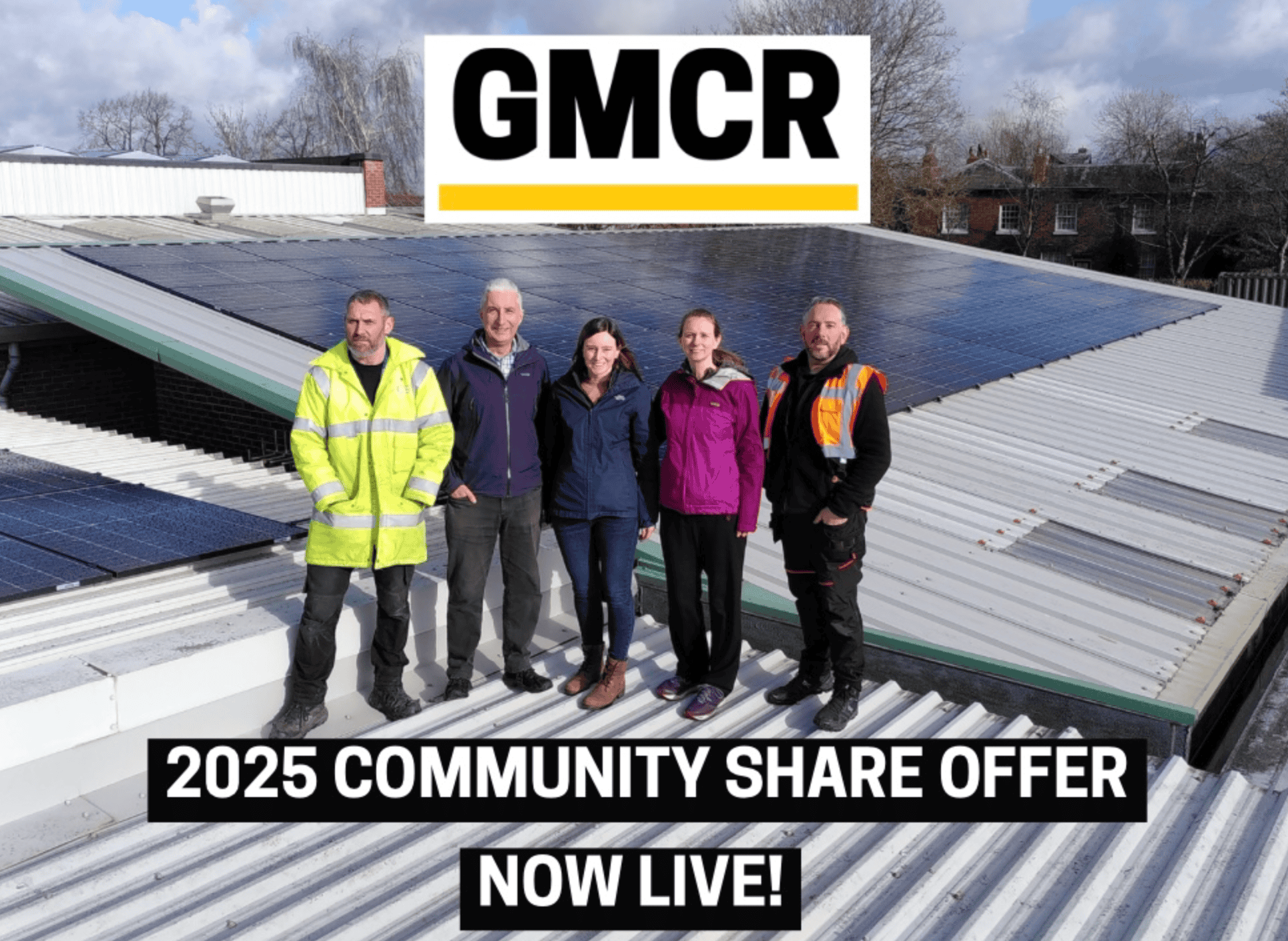 Image of the GMCR team standing on a roof with solar panels installed. 