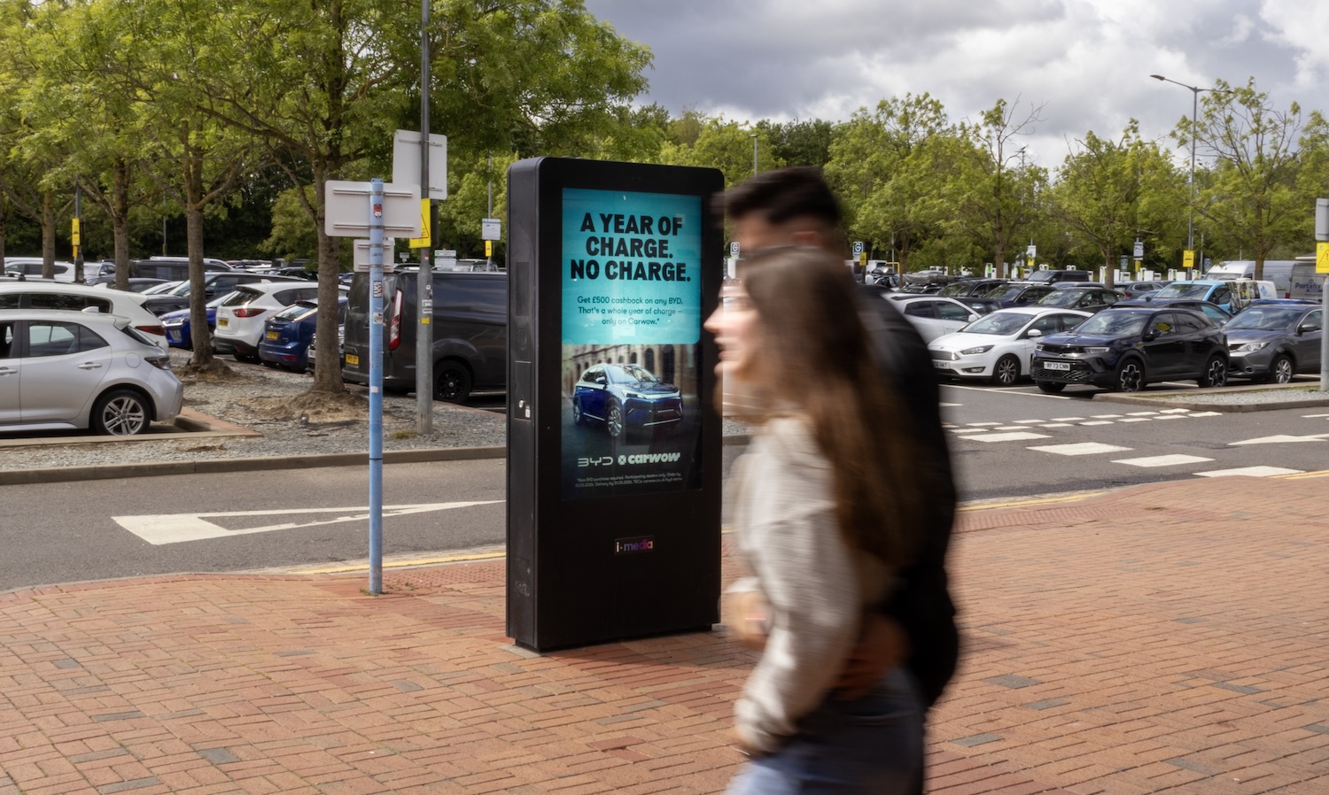 Traveller walking past a Digital 6 screen in a service area car park