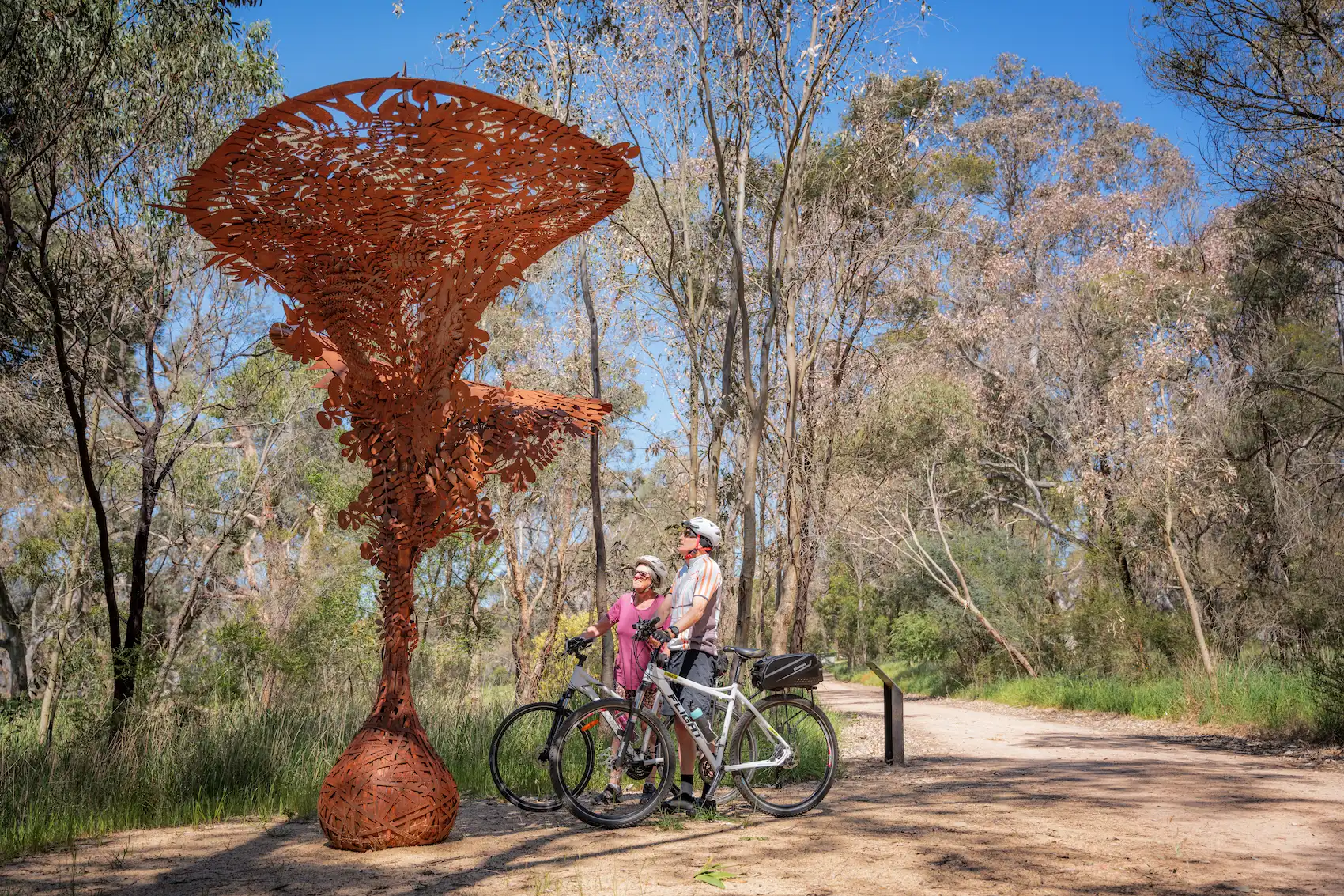 Bikers under an art piece