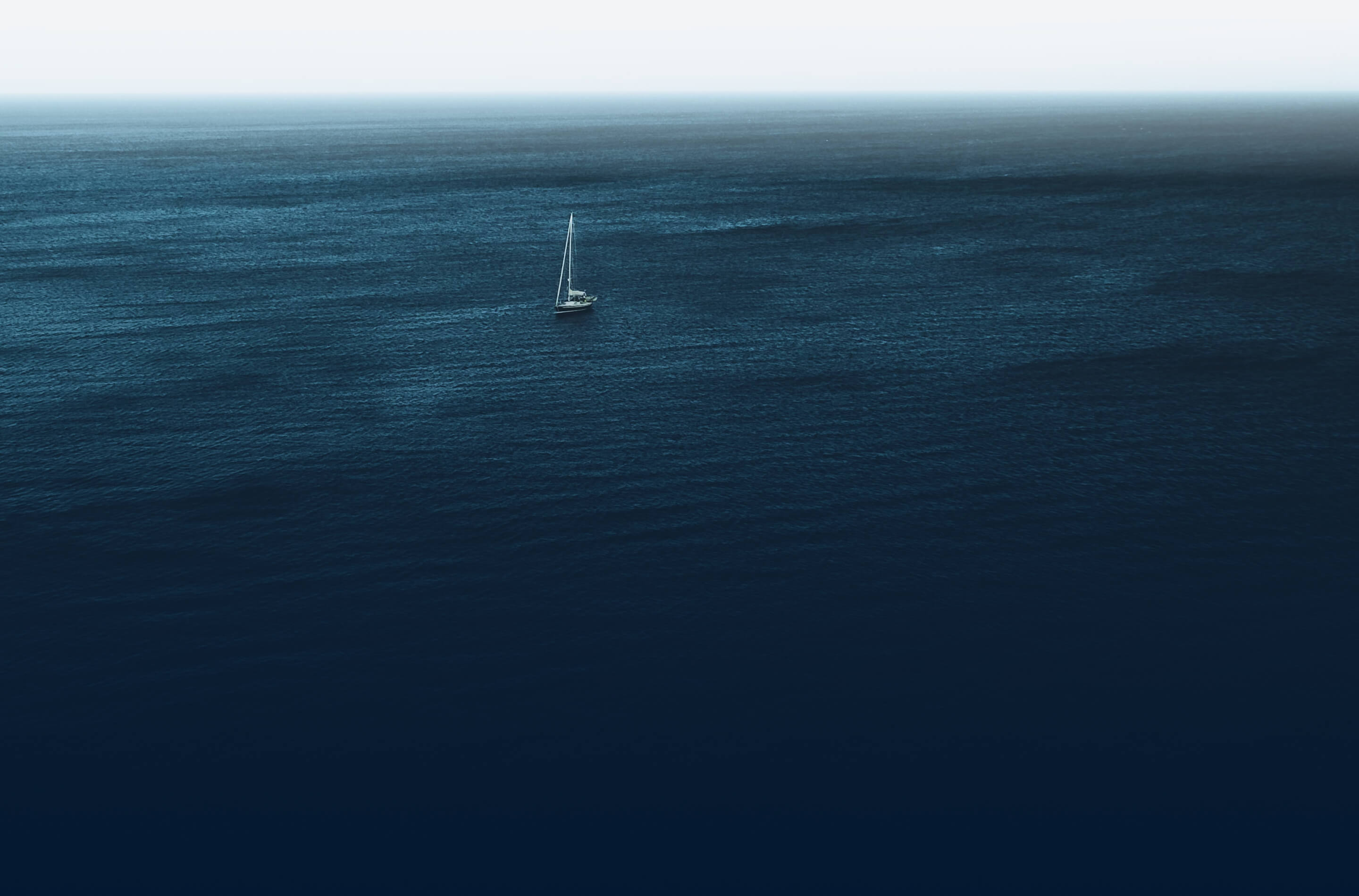 A sailboat in the middle of the ocean.