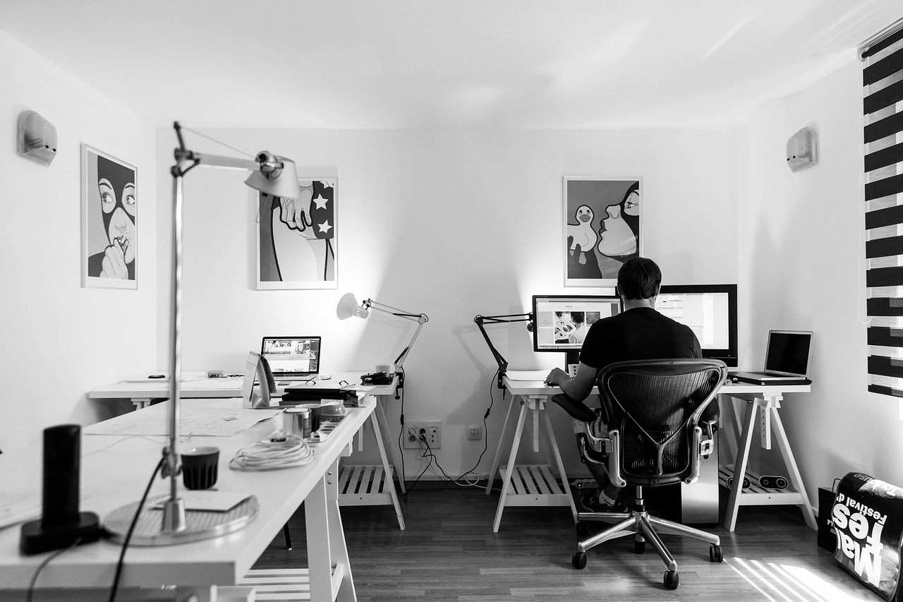 A person seated at a desk working at a computer in a calm, well-organised workspace, with simple furnishings and soft natural light