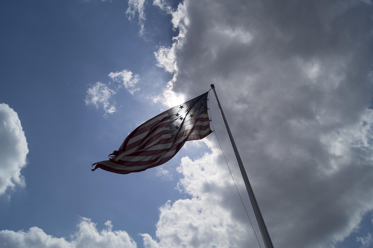 The US flag flying against a sky of shifting clouds