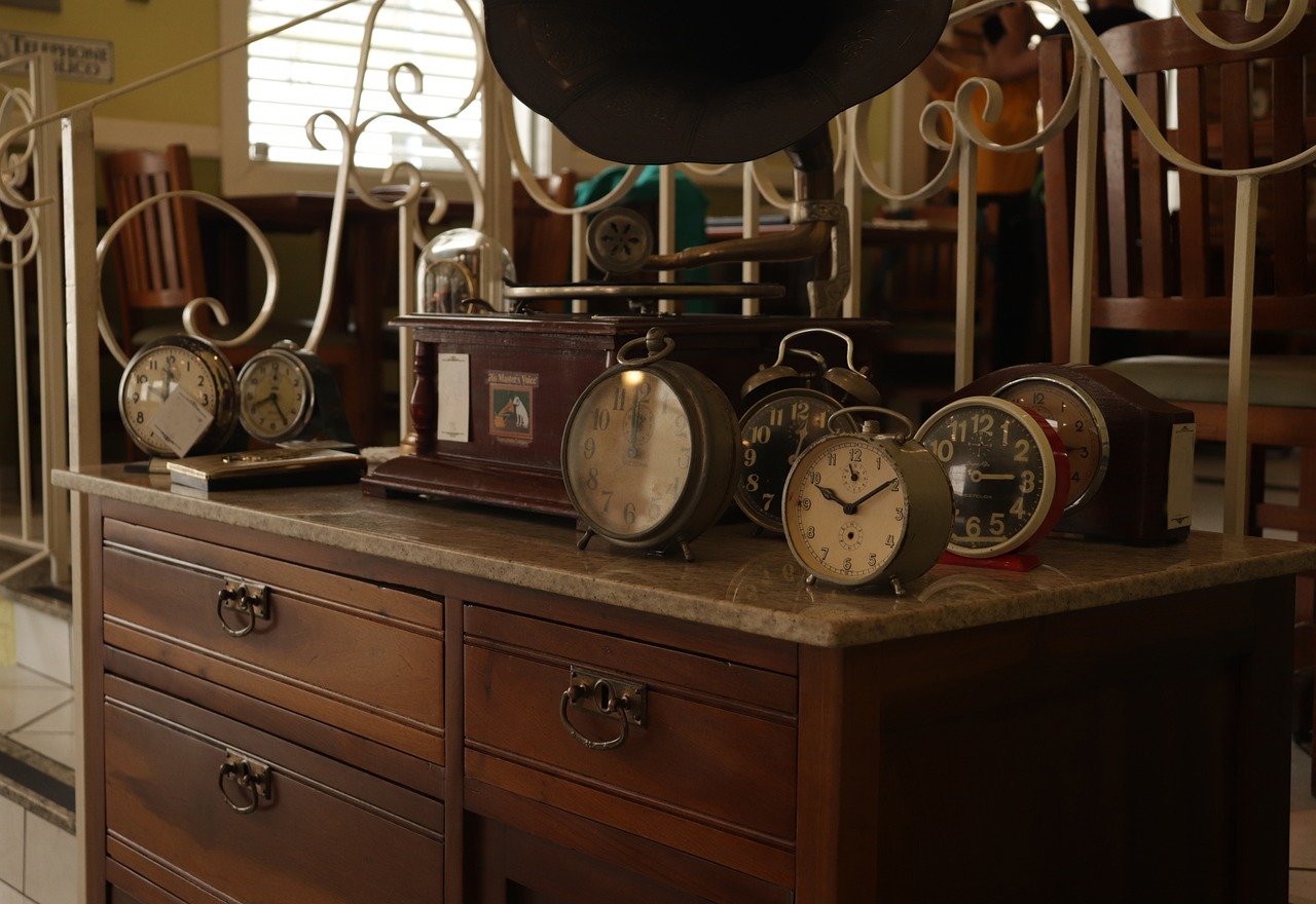 Collection of vintage clocks and an antique gramophone displayed on a wooden cabinet