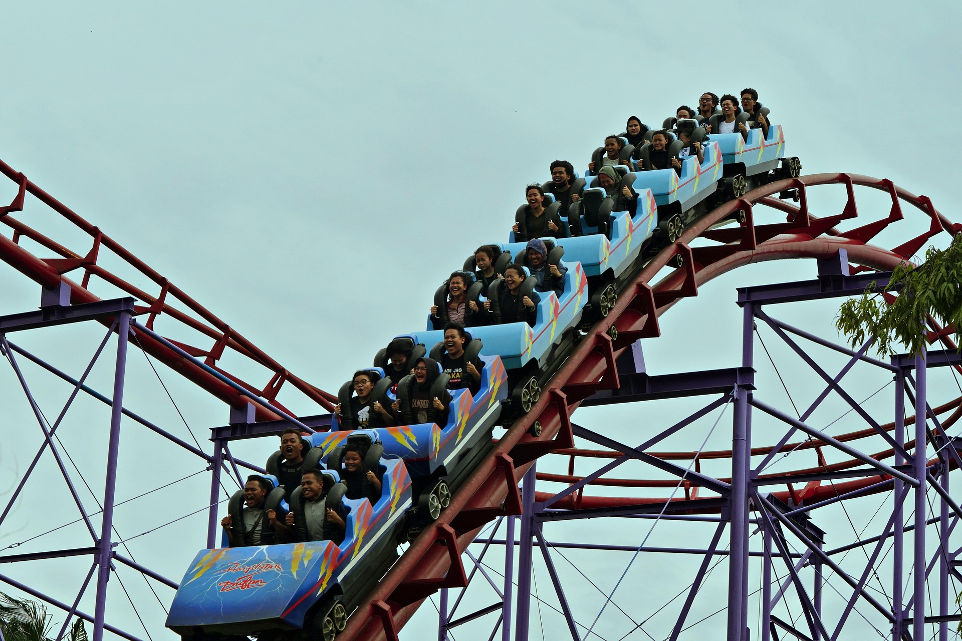 A rollercoaster mid-ride with passengers reacting to a steep dip, capturing a mix of excitement and tension as the track curves downward