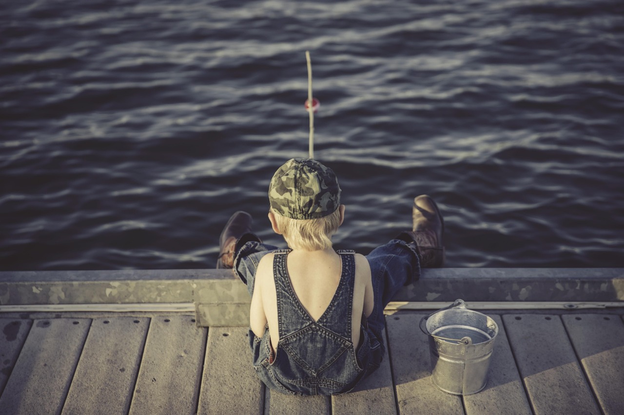 A person sitting on a dock fishing over calm water