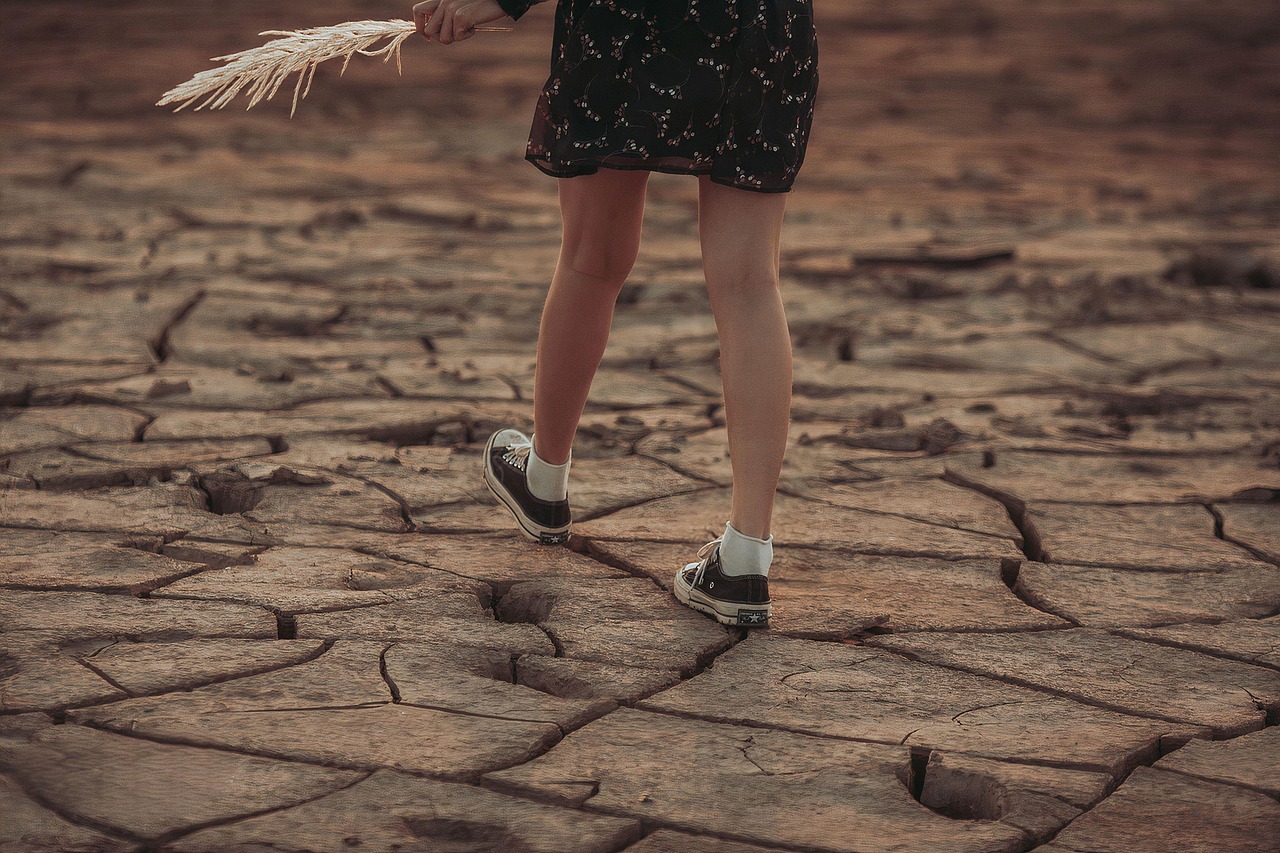 A person standing on cracked ground, representing moments when the world changes shape and people need solid footing