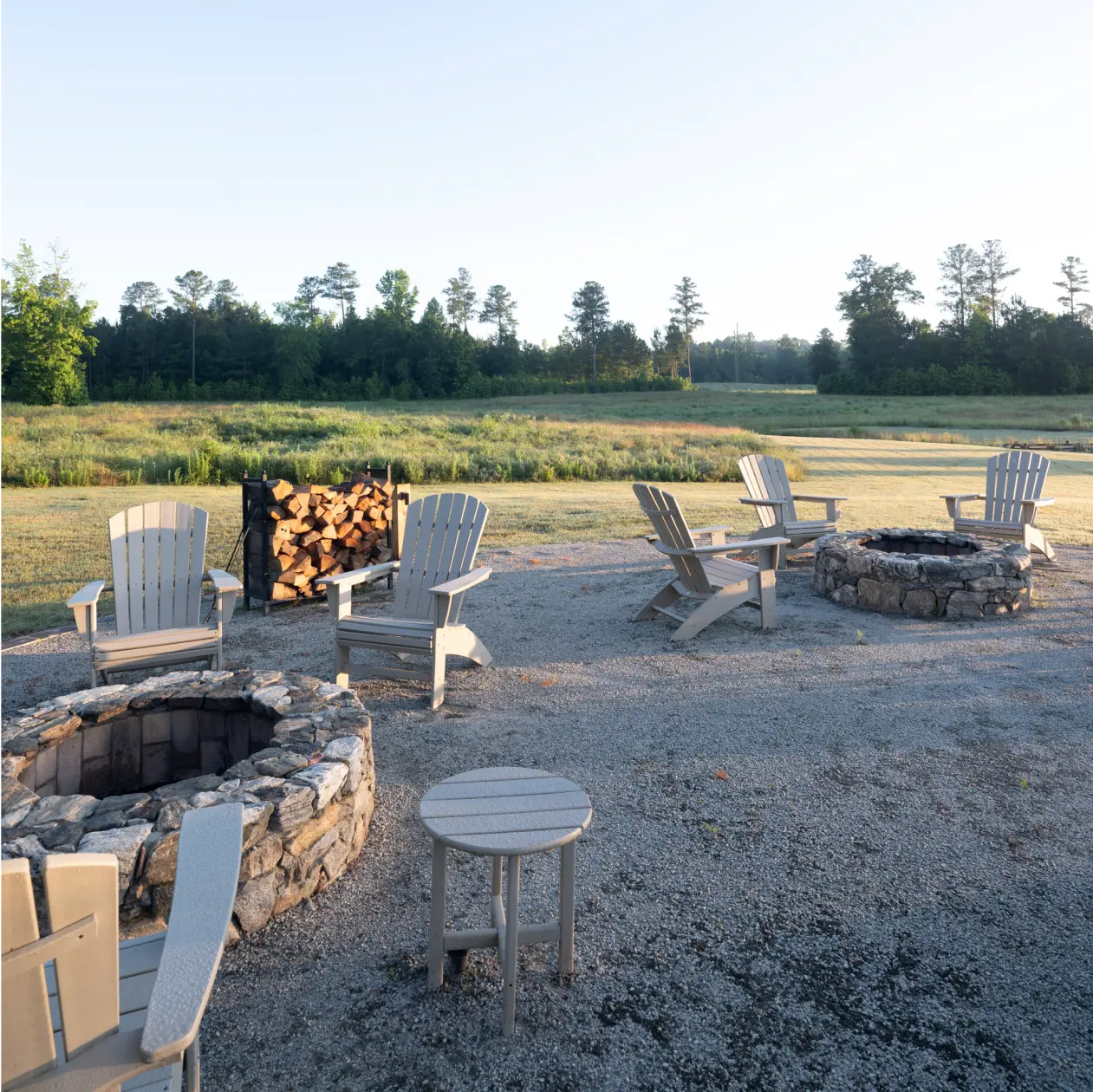 Two stone fire pits with Adirondack chairs and a firewood rack at Heritage
