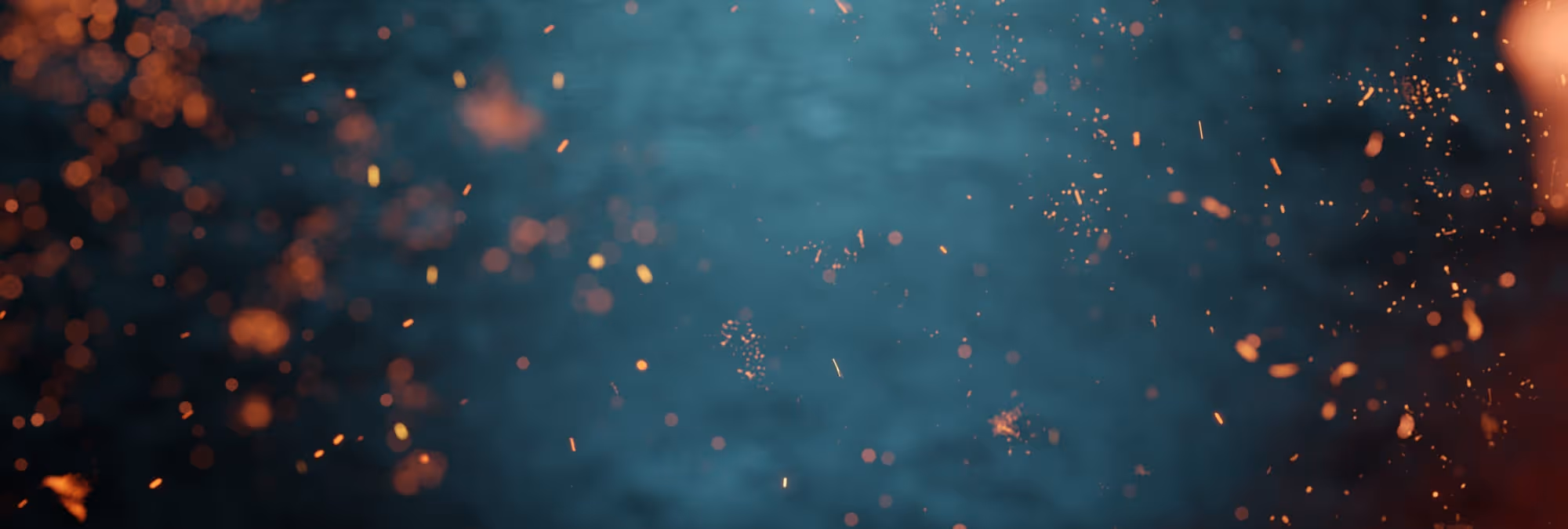 Flammen und glühende Funken vor verschwommenem blauem Hintergrund.