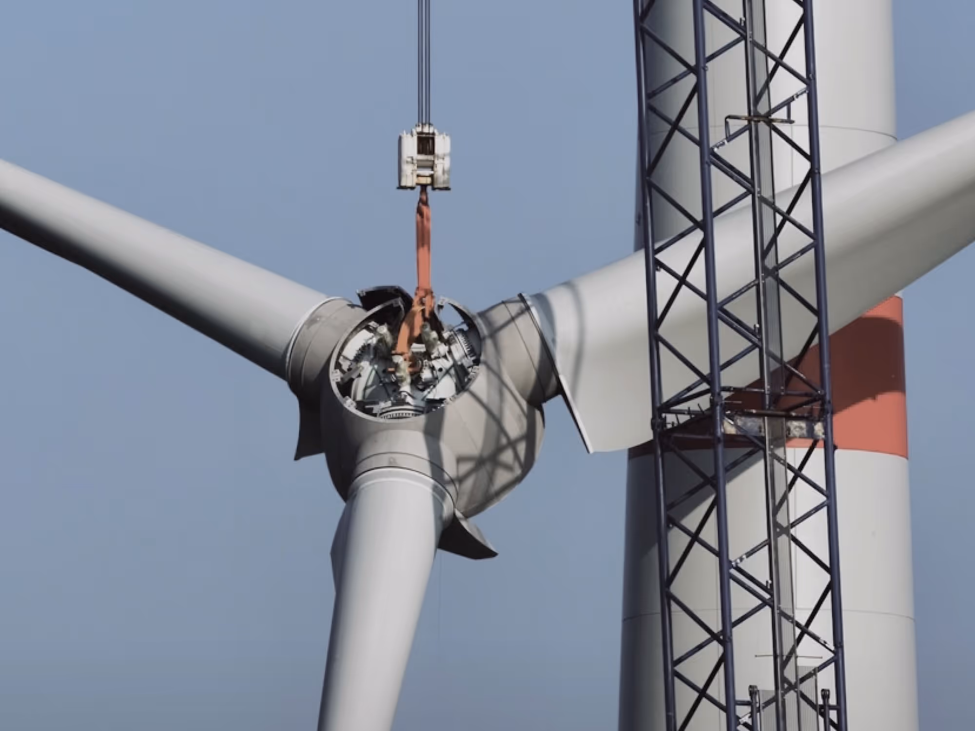 Nahaufnahme einer Windkraftanlage, bei der das Rotorblattgehäuse durch einen Kran für Wartungsarbeiten geöffnet wurde.