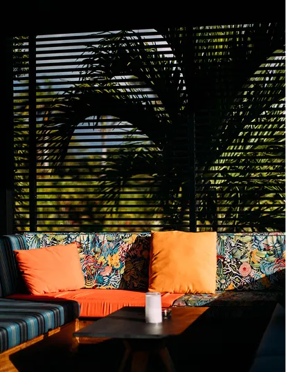 Two daybeds with colorful cushions on a wooden deck, offering panoramic views of the Caribbean Sea through a glass railing. Ideal for a luxury hotel or a villa overlooking the sea in Guadeloupe.