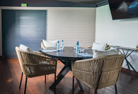 Round meeting table with rattan chairs and bottles of water, in a bright room, typical of a luxury hotel in Guadeloupe.