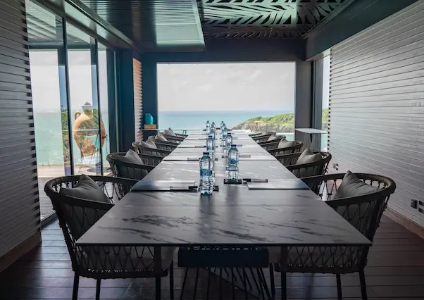 Long conference table with modern chairs and a breathtaking view of the Caribbean Sea through large windows, ideal for luxury meetings in a 5-star hotel in Guadeloupe.