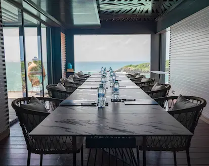 Long conference table with modern chairs and a breathtaking view of the Caribbean Sea through large windows, ideal for luxury meetings in a 5-star hotel in Guadeloupe.