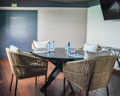 A modern round table with rattan chairs and bottles of water, in a bright meeting room in a luxury hotel in Guadeloupe. Analysis