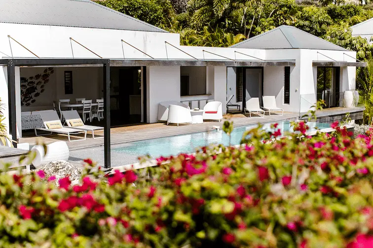 Villa blanche de luxe avec piscine privée et terrasse fleurie à La Toubana Hôtel & Spa en Guadeloupe.
