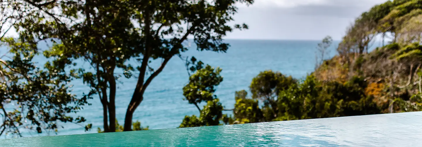 Infinity pool overlooking the Caribbean Sea and the vegetation. This luxurious setting is typical of a 5-star hotel in Guadeloupe or a villa overlooking the sea in Sainte-Anne.