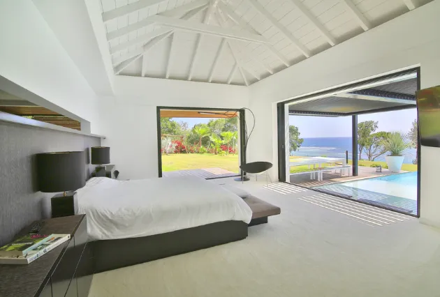 Lit de la villa Ayati à La Toubana Hôtel & Spa, chambre avec vue sur la piscine en Guadeloupe.