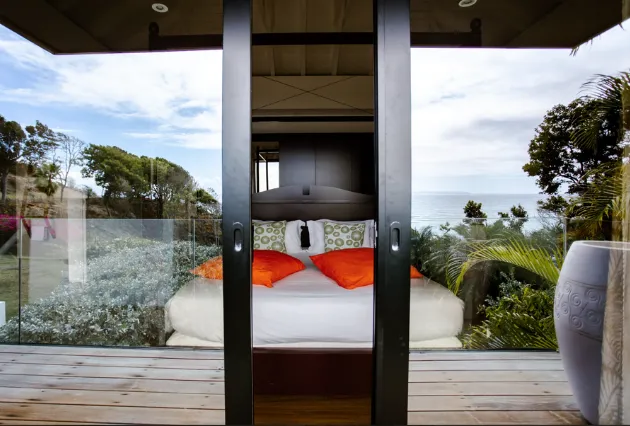 Vue extérieure sur une chambre de luxe à La Toubana Hôtel & Spa, avec lit ouvert sur la terrasse en Guadeloupe.