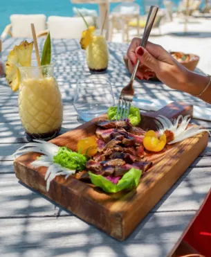 A hearty breakfast with various dishes, including eggs, sausages, sausages, and fresh juices, served on a dark table. Represents the restaurant of a luxury hotel in Guadeloupe.