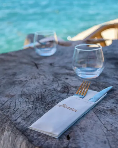 A clear cocktail with a white foam neck and a half-passion on top, placed on a golden platter. Typical of the drinks served in a luxury cocktail bar in Guadeloupe.