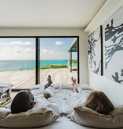 Couple in bathrobes relaxing in a relaxation room with panoramic ocean views, at the spa at La Toubana Hotel & Spa.