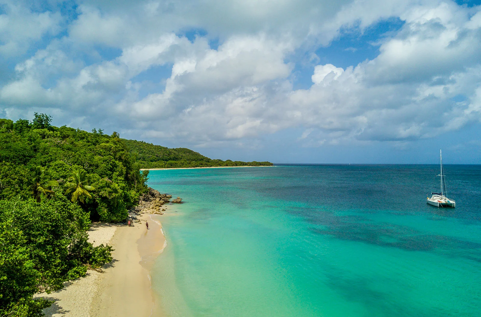 Plage de Marie-Galante en Guadeloupe avec sable blanc, eau turquoise et voilier au large