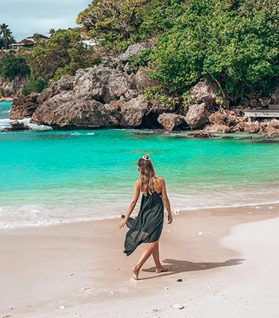 Femme marchant sur une plage turquoise en Guadeloupe, ambiance détente et évasion