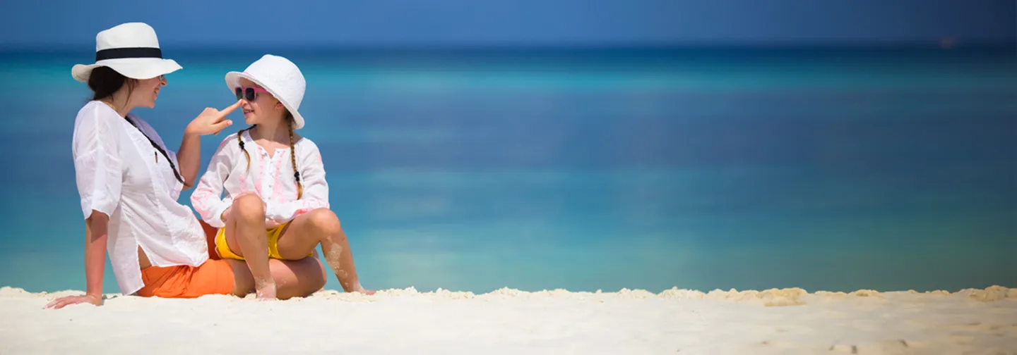 Mère et enfant assises sur la plage face à la mer turquoise en Guadeloupe à La Toubana Hôtel & Spa
