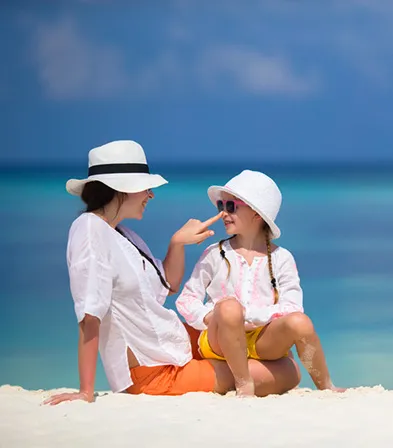 Mère et enfant assises sur la plage face à la mer turquoise en Guadeloupe à La Toubana Hôtel & Spa
