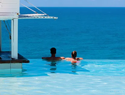Una pareja de espaldas se relaja en la piscina infinita frente al mar en La Toubana Hotel & Spa en Guadalupe