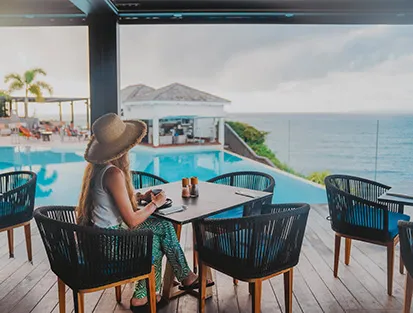 Eine Kundin beim Frühstück auf der Terrasse mit Blick auf den Pool und das Meer im La Toubana Hotel & Spa
