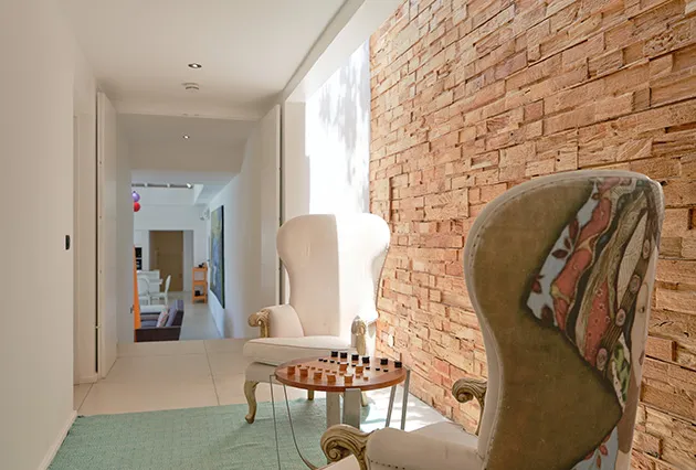 Relaxation area in the Villa Ura hallway featuring armchairs, a chessboard, and a stone-clad wall in Guadeloupe